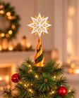Estrela guia com base dourada no topo de uma árvore de Natal decorada