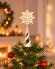 Estrela guia com base branca no topo de uma árvore de Natal decorada
