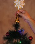 Mão encaixando a estrela guia de base dourada no topo da árvore de Natal